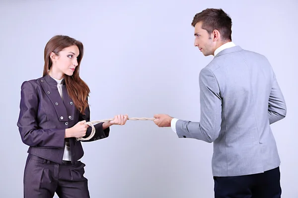 Mensen uit het bedrijfsleven die zich uitstrekt touw op grijze achtergrond — Stockfoto