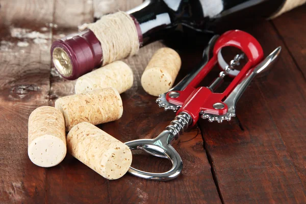 Штопор с винными пробками и бутылкой вина на деревянном столе крупным планом — стоковое фото