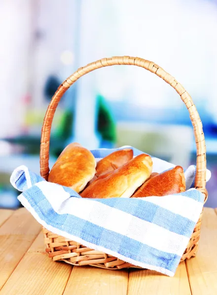Fresh baked pasties in wicker basket, on bright background — Stock Photo, Image