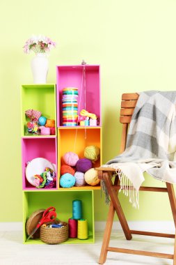 plaid duvar arka planda sandalyeyle yakınındaki eşyaları ile farklı renk renkli raflar