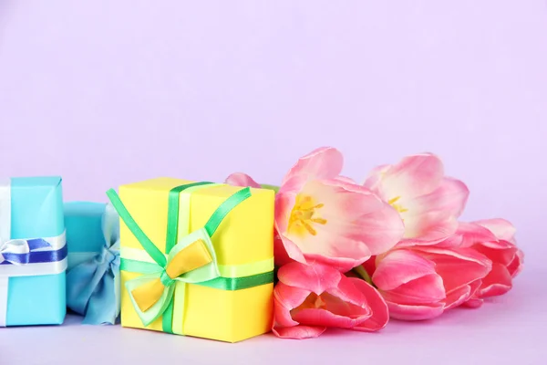 Pink tulips and gift boxes, on color background — Stock Photo, Image