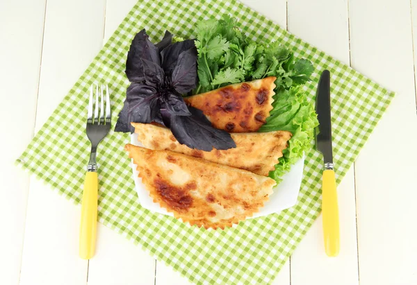 Sabrosos chebureks con hierbas frescas en el plato, sobre fondo de madera de color — Foto de Stock