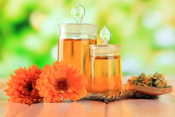 Medicine bottles and calendula flowers on wooden table — Stock Photo, Image