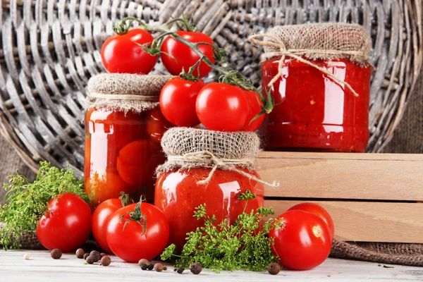 Smaczne konserwy i świeże pomidory na drewnianym stole — Zdjęcie stockowe