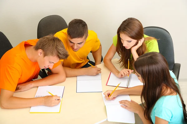 Grupo de jóvenes estudiantes sentados en la habitación — Foto de Stock