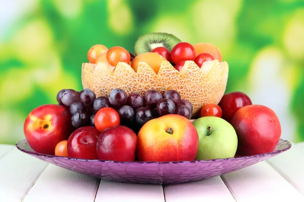 Assortment of juicy fruits on wooden table, on bright background — Stock Photo, Image