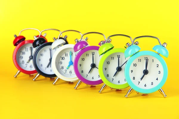 Relógio de alarme colorido no fundo amarelo — Fotografia de Stock