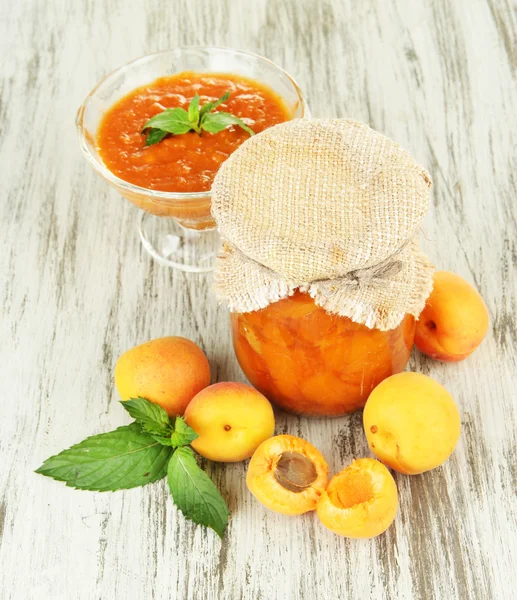 在玻璃罐子和新鲜的杏子，木制背景上的杏酱 — 图库照片