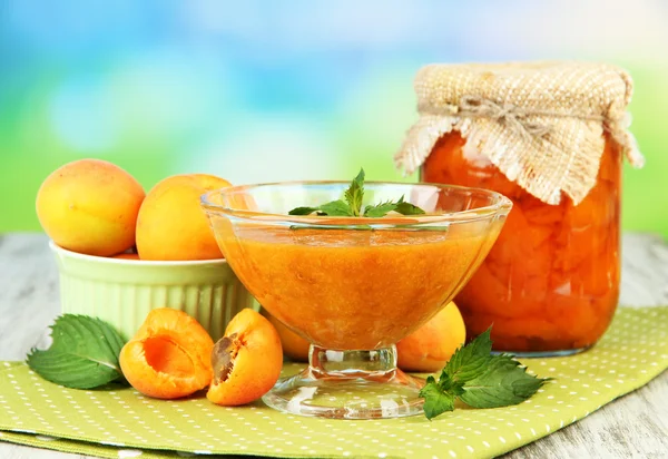 Marillenmarmelade im Glas und frischen Aprikosen, auf Holztisch, auf hellem Hintergrund — Stockfoto