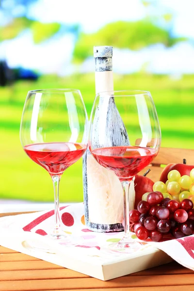 Sklenice vína na ubrousek na zásobník na dřevěný stůl na pozadí přírody — Stock fotografie