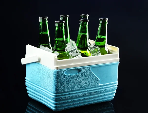 Bottles of beer with ice cubes in mini refrigerator, on dark blue background — Stock Photo, Image