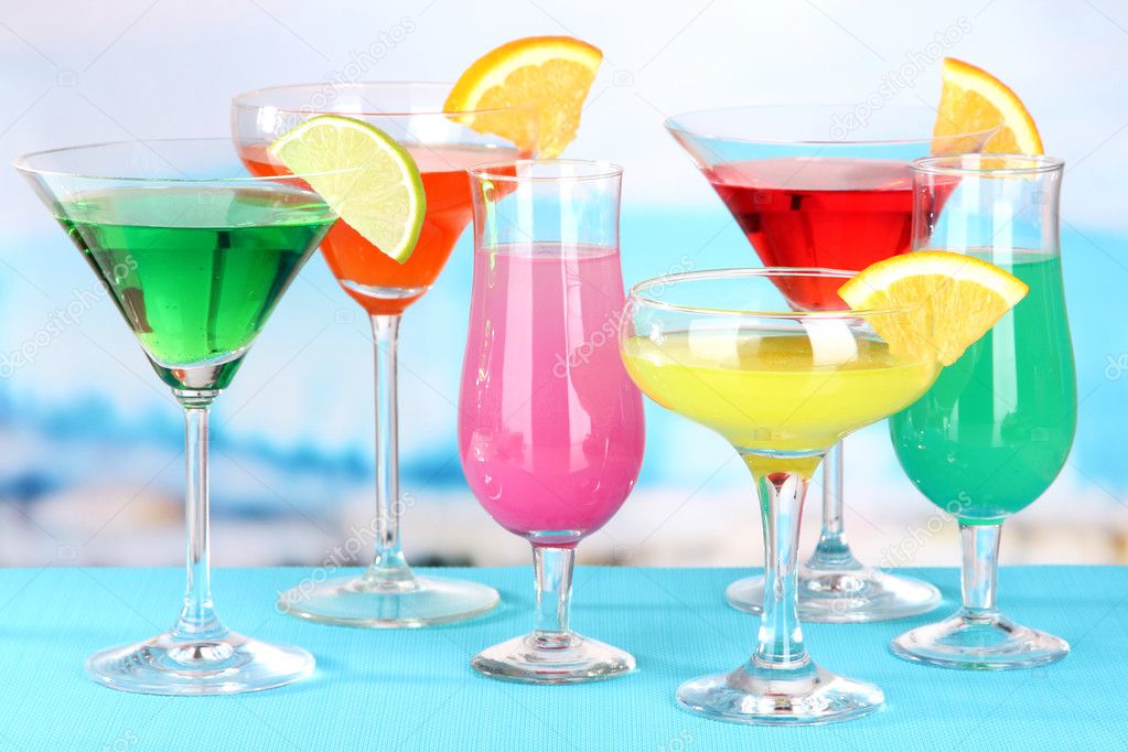 Glasses of cocktails on table near pool