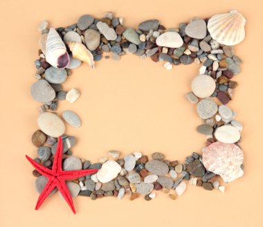 Frame of sea stones on color background clipart