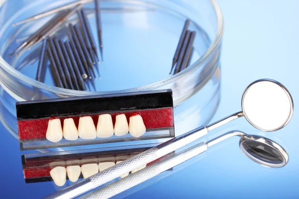 Denture with dental tools on blue background — Stock Photo, Image