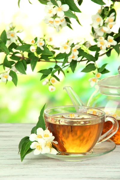 Cup of tea with jasmine, on wooden table, on bright background — Stock Photo, Image