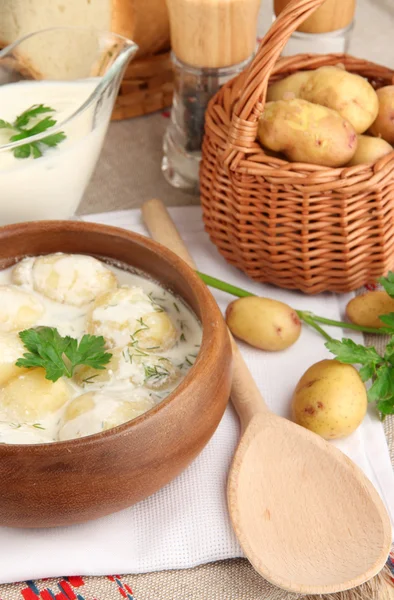 Zarte junge Kartoffeln mit saurer Sahne und Kräutern in hölzerner Schüssel auf Tischdecke in Großaufnahme — Stockfoto