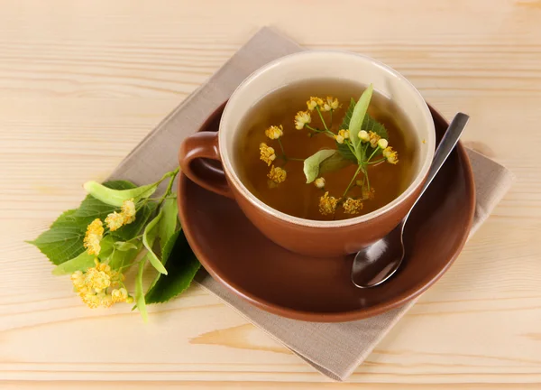 Cup of tea with linden on napkin wooden table — Stock Photo, Image