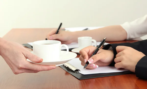 Primer plano de las manos de mujer de negocios con taza de café durante el trabajo en equipo — Foto de Stock
