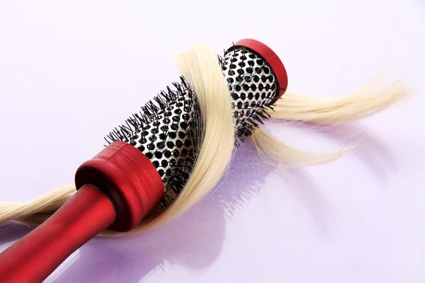 Comb brush with hair, on purple background — Stock Photo, Image