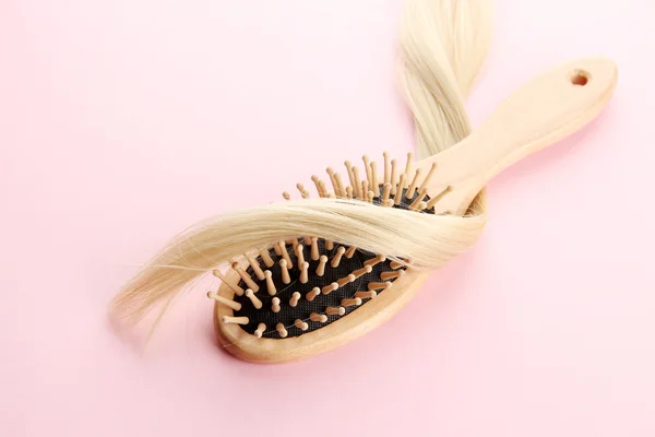 Cepillo peine de madera con pelo, sobre fondo rosa — Foto de Stock