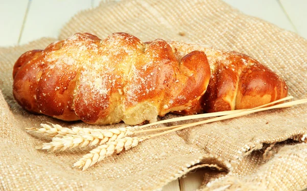 Composition with buns in wicker basket, on wooden table, on color background — Stock Photo, Image