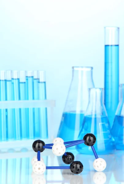 Molecule model and test tubes with liquid on blue background — Stock Photo, Image