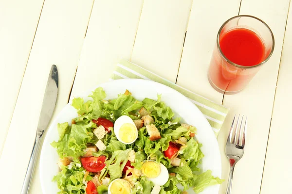 Caesarsalade op witte plaat, op een houten achtergrond kleur — Stockfoto