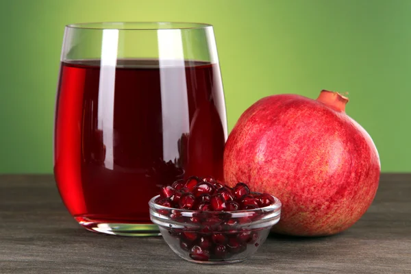 Glass of fresh garnet juice on table on green background — Stock Photo, Image