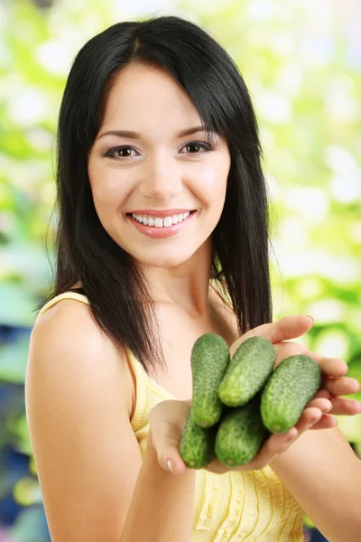 Ragazza con cetrioli freschi su sfondo naturale — Foto Stock