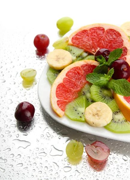 Assortment of sliced fruits on plate with drops — Stock Photo, Image