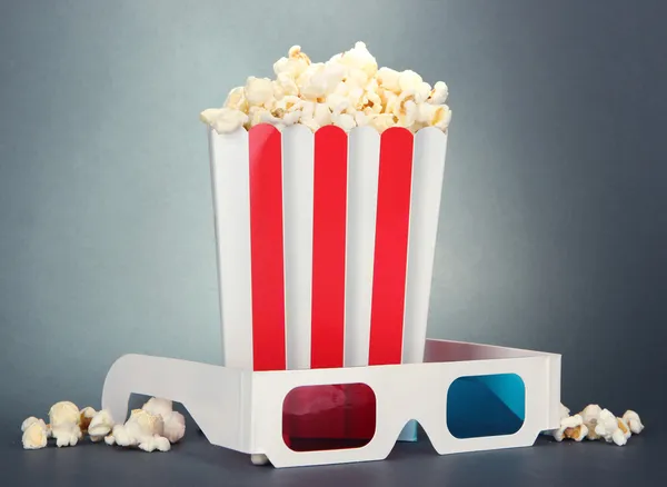 Popcorn e occhiali 3D su sfondo grigio — Foto Stock
