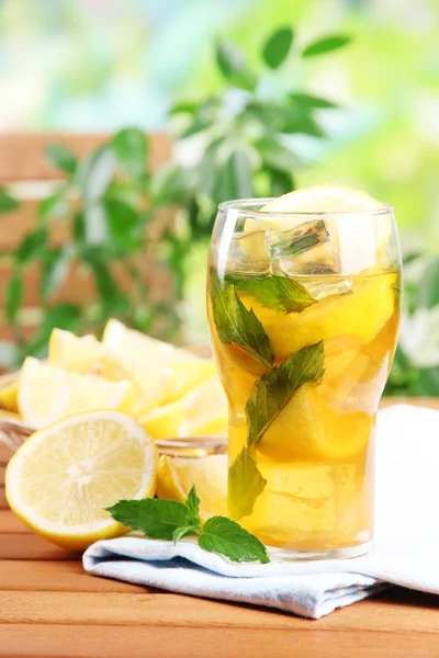 Té helado con limón y menta en la mesa de madera, al aire libre —  Fotos de Stock