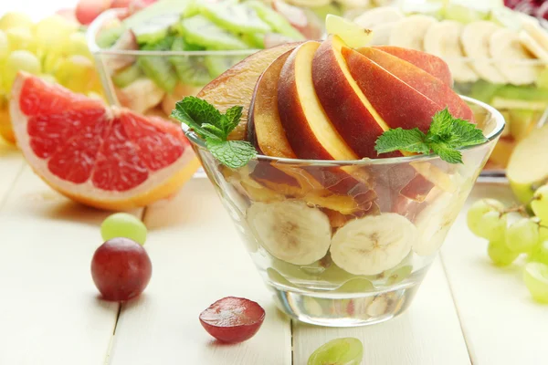 Leckerer Obstsalat in Glasschüssel, auf weißem Holztisch — Stockfoto