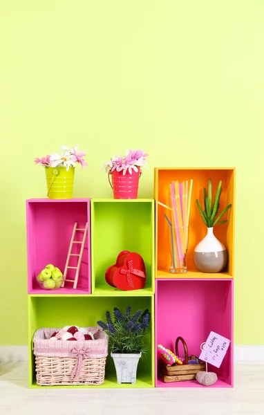 Prateleiras de diferentes cores brilhantes com adição decorativa no fundo da parede — Fotografia de Stock