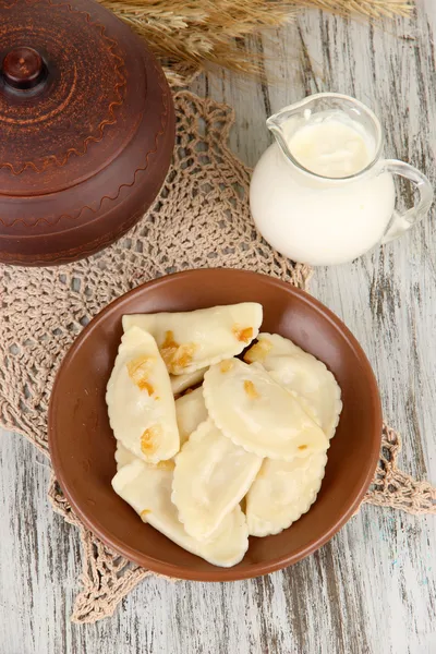 Tasty dumplings with fried onion on brown plate, on wooden background — Stock Photo, Image