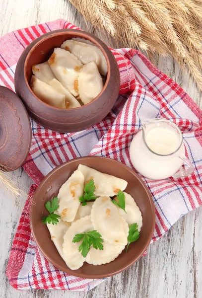 Gnocchi gustosi con cipolla fritta su piatto marrone, su fondo di legno — Foto Stock