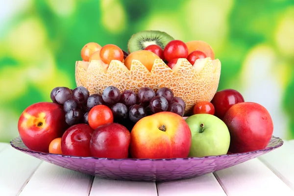 Surtido de frutas jugosas sobre mesa de madera, sobre fondo brillante — Foto de Stock