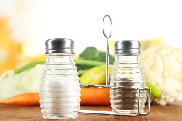 Salt and pepper mills, on wooden table, on bright background — Stock Photo, Image