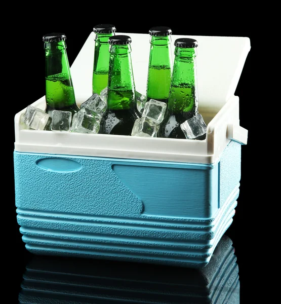 Bottles of beer with ice cubes in mini refrigerator, on black background — Stock Photo, Image