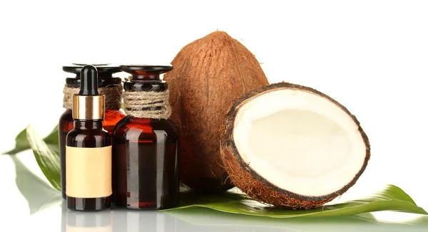 Kokosöl in Flaschen mit Kokosnüssen auf weißem Hintergrund — Stockfoto