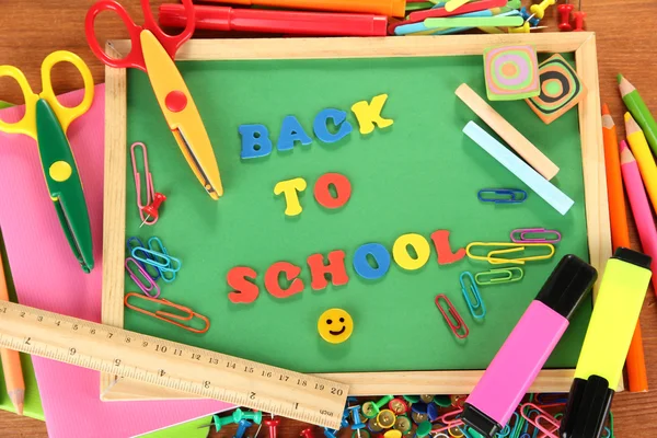 Kleine Kreidetafel mit Schulmaterial auf Holzgrund. Zurück zur Schule — Stockfoto