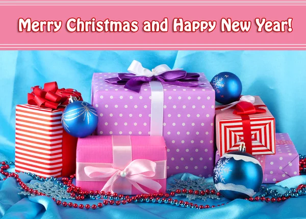 Mavi Noel topları, kar taneleri ve mavi kumaş üzerine boncuk renkli hediyeler — Stok fotoğraf