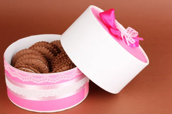 Chocolate cookies with creamy layer on box on brown background — Stock Photo, Image