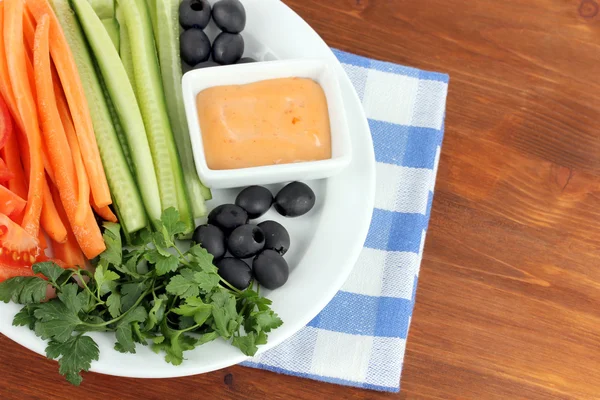 Ассорти сырых овощей палками в тарелке на деревянном столе крупным планом — стоковое фото