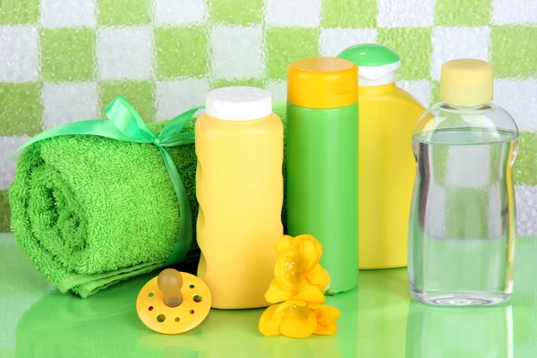 Baby kosmetika och handduk i badrummet på gröna kakel vägg bakgrund — Stockfoto