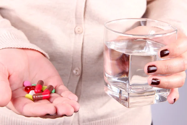 Beaucoup de pilules et d'eau en verre à la main — Photo