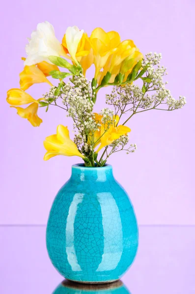 Mooi boeket van fresia's in vaas op paarse achtergrond — Stockfoto