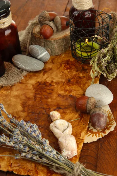 Composition with old papers, herbs, stones and bottles with symbols on wooden background — Stock Photo, Image