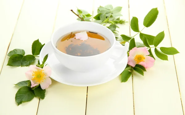 Tazza di tisana con fiori di rosa mosqueta sul tavolo di legno bianco — Foto Stock