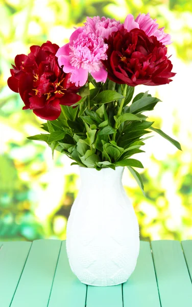 Schöne Pfingstrosen in der Vase auf dem Tisch auf hellem Hintergrund — Stockfoto